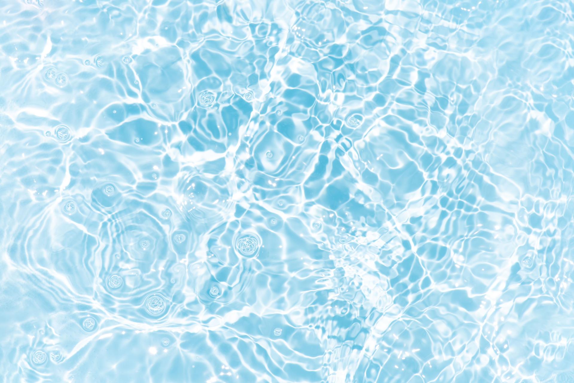 Blue water with ripples on the surface. Defocus blurred transparent blue colored clear calm water surface texture with splashes and bubbles. Water waves with shining pattern texture background.